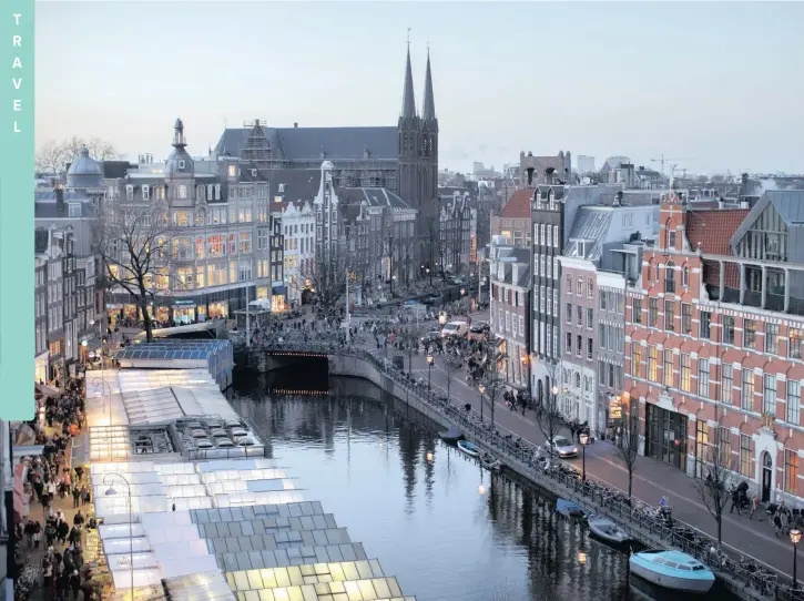  ?? Bloomberg ?? Flower stalls, left, float illuminate­d on a canal at the Bloemenmar­kt as the Kalverton retail mall sits on the opposite bank in Amsterdam. Cover: Reykjavik in Iceland.