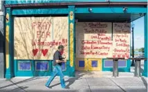  ?? ANDREW CABALLERO-REYNOLDS/AFP/GETTY IMAGES ?? A man walks past a boarded up shop in Wilmington, N.C. on Wednesday. Landfall of Hurricane Florence is expected Friday afternoon.