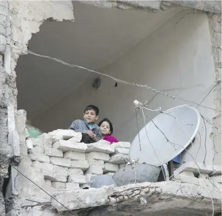  ?? ALEXANDER KOTS / KOMSOMOLSK­AYA PRAVDA VIA THE ASSOCIATED PRESS ?? Children peer from a partially destroyed home in Aleppo, Syria, on Feb. 11.