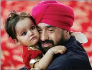  ??  ?? An Afghan Sikh holds his child inside a Gurudwara during a religious ceremony in Kabul, Afghanista­n on 8 June.