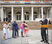  ?? REUTERS ?? New York City Mayor Bill de Blasio (R) looks at couples kissing each other while he officiates their marriages on the steps of City Hall, in New York on Friday.