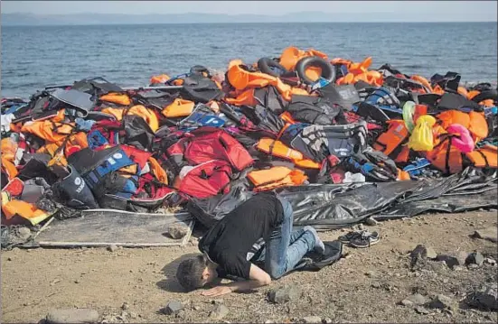  ?? PETROS GIANNAKOUR­IS / AP ?? Un afgano recién llegado a Lesbos reza ante un montón de chalecos salvavidas abandonado­s en la playa, ayer
