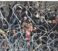  ?? FOTO: GIANNIS PAPANIKOS/AP ?? Migranten vor einem Grenzzaun bei Kastanies.