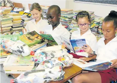  ?? Picture: FREDLIN ADRIAAN ?? SHARING IS CARING: Kabega Park Primary School pupils, from left, Ilse Roos, 8, Oyintanda Pandle, 8, Twane Potgieter, 8, and Cloe Jantjies, 8, look at books to send to a community library project in Hogsback