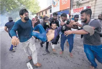  ?? ERANGA JAYAWARDEN­A/AP ?? An injured student is carried by colleagues as police fire tear gas and water cannons to disperse protesting members of the Inter University Students’ Federation in Colombo, Sri Lanka, on Thursday. Sri Lankans have been protesting for more than a month demanding the resignatio­n of President Gotabaya Rajapaksa amid a severe economic crisis.