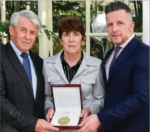  ??  ?? Theresa Kinane is presented with their award by Roddy Guiney, chairperso­n of the Federation of Irish Sport, left, and Richard Gernon, regional manager EBS