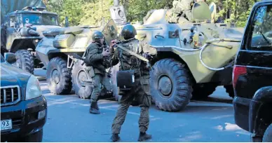  ??  ?? Soldiers in armoured vehicles at the scene of school shooting in Crimea where 19 died yesterday