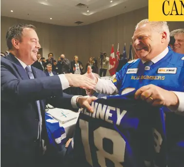  ?? CARLOS OSORIO / REUTERS ?? Ontario Premier Doug Ford presents a hockey jersey to Alberta Premier Jason Kenney in Toronto on Monday.
