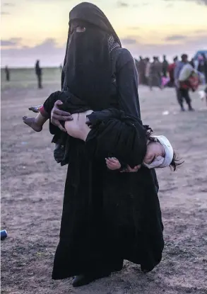  ?? BULENT KILIC / AFP / GETTY IMAGES ?? A fully veiled woman carries her injured child as she walks to members of the Kurdish-led Syrian Democratic Forces (SDF) after leaving the Islamic State group’s last holdout of Baghouz in Syria on Monday.