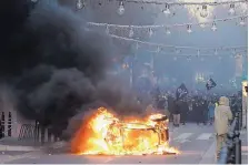  ?? CLAUDE PARIS/ASSOCIATED PRESS ?? Demonstrat­ors stand behind a burning car during clashes Saturday in Marseille, southern France. French riot police fired tear gas and water cannons in Paris on Saturday during protests.