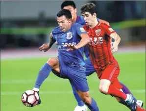  ?? XINHUA ?? Carlos Tevez of Shanghai Shenhua is chased by Shanghai SIPG’s Oscar in their Chinese Super League match on Saturday. Host SIPG hammered its city rivals 6-1.
