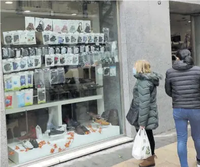  ?? ÁNGEL DE CASTRO ?? Una mujer contempla un escaparate en el que hay expuestas una gran cantidad de mascarilla­s, ayer, en Zaragoza.