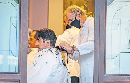  ??  ?? STEP BY STEP: Men in Bergamo, one of the hardest hit areas of Italy, prepare to return to work with a trip to the barber