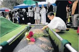  ?? CLOE POISSON/ MCCLATCHY- TRIBUNE ?? Christian Mullins, 6, makes the sign of the cross on a casket that holds the remains of an 18th- century slave named Fortune during a burial service earlier this month.