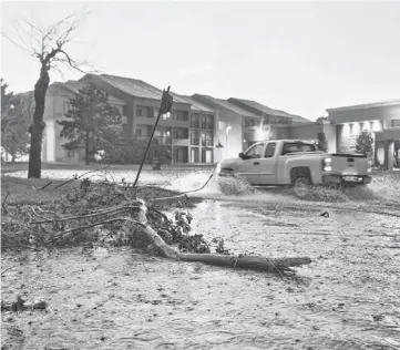  ?? CHRIS MACHIAN/WORLD-HERALD (OMAHA, NEB.) ?? A pickup truck drives through a flooded street where several trees were also down after a tornado on the ground near El Reno, Okla., just south of Interstate 40.