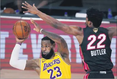  ?? MARK J. TERRILL - STAFF, AP ?? Los Angeles Lakers’ LeBron James, left, looks to pass while being pressured by Miami Heat’s Jimmy Butler during the second half of Wednesday’s game in Lake Buena Vista, Fla.