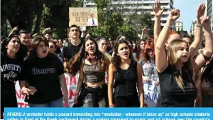  ?? — AFP ?? ATHENS: A protester holds a placard translatin­g into “revolution - wherever it takes us” as high schools students gather in front of the Greek parliament during a protest organised by music and art schools over the country’s worst rail tragedy that killed 57 people last week.