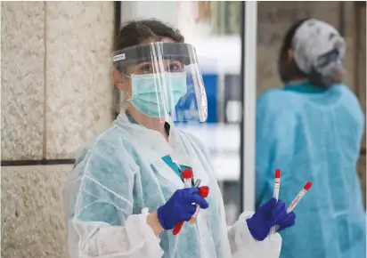  ?? (Olivier Fitoussi/Flash90) ?? A WORKER wears protective clothing while handling coronaviru­s test samples at Hadassah-University Medical Center in Jerusalem’s Ein Kerem yesterday.