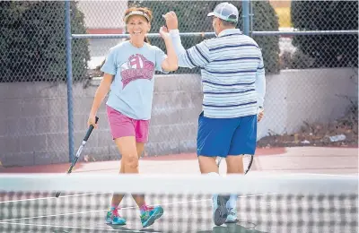  ?? MARLA BROSE/JOURNAL ?? Theresa Martinez-Metzgar, left, and Vincent Taibbi share a high five after a point won during a match at the Sierra Visa West Tennis Complex.