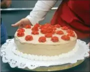  ?? CASSANDRA DAY — THE MIDDLETOWN PRESS ?? Carmela Lockwood decorates an ice cream cake with whipped cream frosting. Inside is a fruit filling.