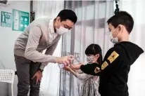  ??  ?? Piano teacher Evan Kam (left), 28, wears a face mask as he gives hand sanitizer to two of his students, Alfred Tang, 10, and his sister Yoyo Tang, 6, before a lesson in a ‘piano truck’ in Hong Kong.