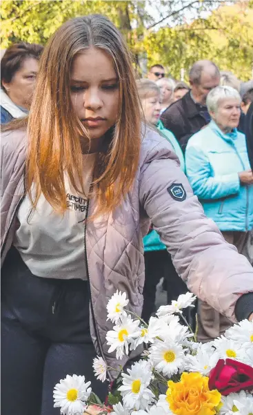  ??  ?? MOURNING: A woman lays flowers for the victims. Picture: AFP