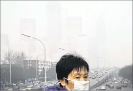  ?? ANDY WONG / ASSOCIATED PRESS 2015 ?? A woman wears a mask for protection as office buildings are shrouded with smog in December in Beijing. Nearly two-thirds of air pollution deaths each year are in Southeast Asia and the Western Pacific region, a study found.