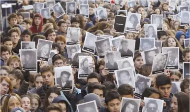  ?? (Enrique Marcarian/Reuters) ?? MEMBERS OF THE Argentinea­n Jewish community in Buenos Aires hold up pictures of the victims of the AMIA Jewish center bombing, during a ceremony in 2015 to mark the 21th anniversar­y of the 1994 attack.