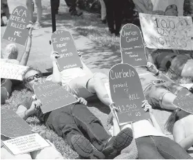  ??  ?? Pro-Obamacare demonstrat­ors lie down during a protest outside the office of Florida Republican Congressma­n Carlos Curbelo Thursday in Miami.