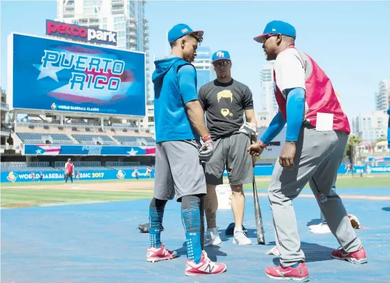  ??  ?? Francisco Lindor y Javier Báez escuchan al instructor de bateo Carlos Delgado durante la sesión de entrenamie­nto de ayer.