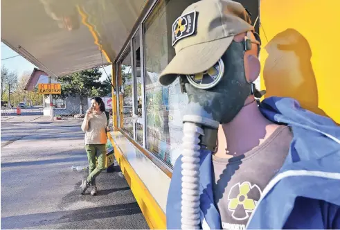  ??  ?? Eine Besucherin trinkt Kaffee vor einem Souvenir-Shop am Zugang zur Sperrzone rund um das zerstörte Atomkraftw­erk.