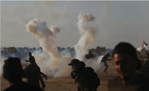  ?? (Reuters) ?? TEAR GAS lands among protesters in the Gaza Strip.