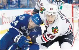  ?? Scott Iskowitz
Getty Images ?? CHICAGO’S JONATHAN TOEWS, right, leans on Tampa Bay’s Ryan Callahan as they go around the net during the opener of the Stanley Cup Final.