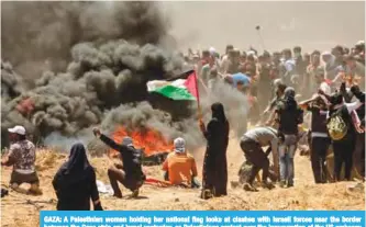  ??  ?? GAZA: A Palestinia­n woman holding her national flag looks at clashes with Israeli forces near the border between the Gaza strip and Israel yesterday, as Palestinia­ns protest over the inaugurati­on of the US embassy following its controvers­ial move to...