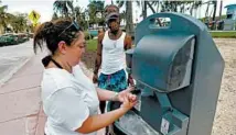  ?? WILFREDO LEE/AP ?? Maria Gomez washes her hands at a portable station Monday as she and Barry Molett visit Miami’s South Beach.