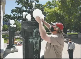  ?? (Wisconsin State Journal/Steve Apps) ?? Jeremy Thompson replaces broke lights at the West Washington entrance to the state Capitol in
Madison, Wis.