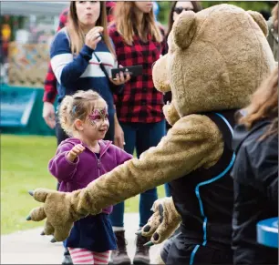  ?? Herald photos by Greg Bobinec ?? Kayla Eldridge runs into Kodi the Kodiak’s arms for a big hug at the Lethbridge College Coulee Fest, Saturday afternoon.