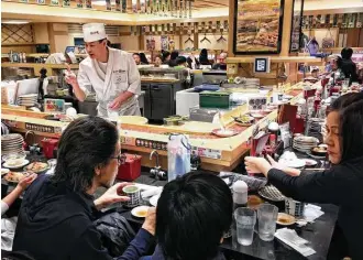  ?? Amelia Rayno photos / Minneapoli­s Star Tribune ?? Top: Even with its big-city hustle and bustle, Toyko is a friendly place, filled with people who take time to help strangers. Above: A helpful man, who spoke no English, stopped what he was doing to guide the writer to Katsu, a conveyer-belt sushi...