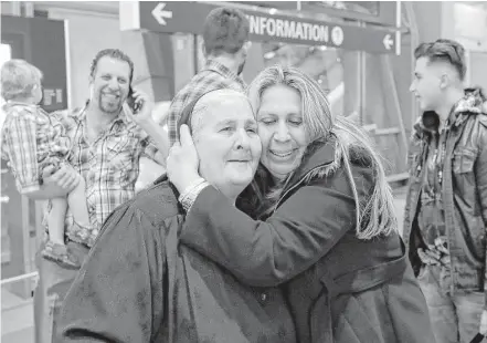  ?? Gregory Bull / Associated Press ?? Nadia Hanan Madalo, center right, hugs her mother, Alyshooa Kannah, left, at the airport after arriving from Iraq on Wednesday in San Diego. Madalo and her family were forced to flee their town after the Islamic State invaded and destroyed it.