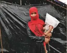  ?? Reuters ?? A Rohingya refugee waits in the rain outside a camp in Cox’s Bazar, Bangladesh, yesterday.