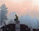  ?? JAE C. HONG/AP ?? Walter Villalobos of the Cosumnes Fire Department stands on top of a fire truck as the sun is visible through smoke generated by the Caldor Fire near South Lake Tahoe, Calif.