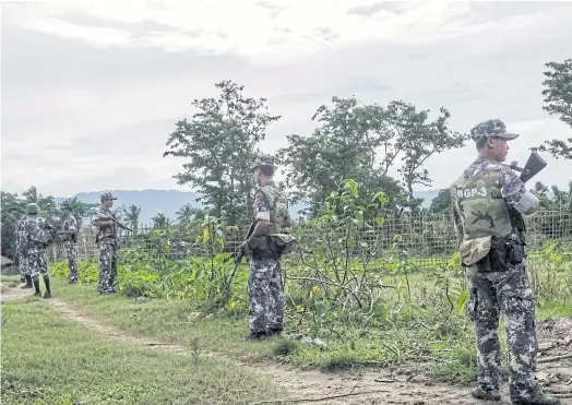  ??  ?? STATE OF FEAR: Border police standing guard at the entrance of Tinmay village in Buthidaung township in Myanmar’s northern Rakhine state.