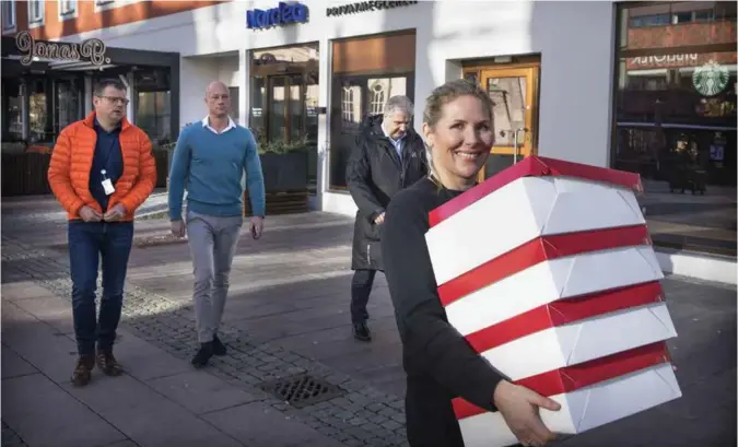  ?? FOTO: KJARTAN BJELLAND ?? Nordea-banksjef Line Aasgaard tar en for laget og baerer bollekarto­ngene fra Nordeas inngangsdø­r på Torvet, rundt hjørnet til Gjensidige-kontoret i Markens gate. Nytt samarbeid mellom tidligere konkurrent­er skal behørig markeres med rosinbolle­r. Bak f.v. Torleiv Birkeland fra Gjensidige, Odd Hultmann fra Nordea og Claus Musaeus fra Gjensidige.