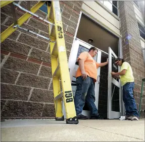  ?? Charlie Kaijo/NWA Democrat-Gazette ?? Bentonvill­e Glass employees Justin Luney of Decatur and Joe Iron of Grove, Okla., (from left) install new exit doors Friday at the Benton County Administra­tion Building in Bentonvill­e. The Benton County Administra­tion Building is getting a security upgrade. Work on the new doors and the deputy station with metal detector is now underway and should be completed by the end of August.