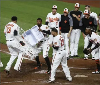  ?? Patrick Semansky ?? The Associated Press Orioles outfielder Adam Jones, second from left, throws ice water at teammate Manny Machado (13) after Machado hit a two-run home run in the ninth inning against the Yankees in Baltimore.