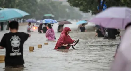  ?? AFP ?? Algunas personas tratan de movilizars­e entre las aguas que dejó la inundación en una calle de Zhengzhou, China, el martes anterior.