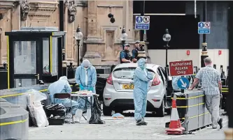  ?? FRANK AUGSTEIN THE ASSOCIATED PRESS ?? Forensics officers work near the Ford Fiesta that crashed into security barriers outside the Houses of Parliament in London, Tuesday. The driver, a man in his 20s, was arrested on suspicion of terrorist offences.