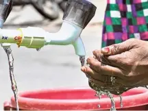  ?? K. MURALI KUMAR ?? A woman drinking potable water from a temporary 1,000-litre storage tank installed on the roadside at Bangarappa­nagar, Rajarajesh­wari Nagar zone, in Bengaluru on Friday.