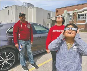  ?? STEPH CROSIER ?? Dean Roberts, from left, with sons Alex, 12, and Josh 8, at Frontenac Secondary School on Monday. The Roberts family travelled to Kingston from Oshawa to take in the eclipse while in totality.