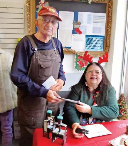  ??  ?? Dot Harner, who coordinate­s the volunteers, stamps Christmas cards for Noel resident Jim Stauber.